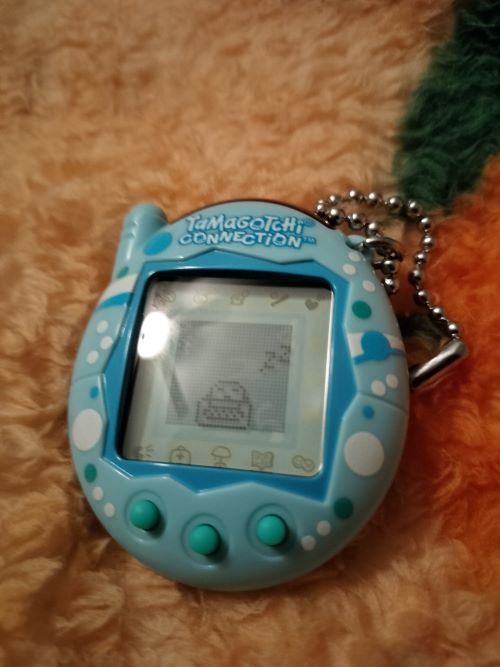 photo of a tamagotchi device. it's light blue with spots and teal buttons.